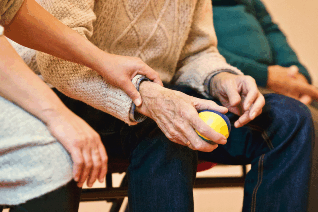 Main d’une personne âgée tenant une balle de rééducation, accompagnée par une main plus jeune en signe de soutien.